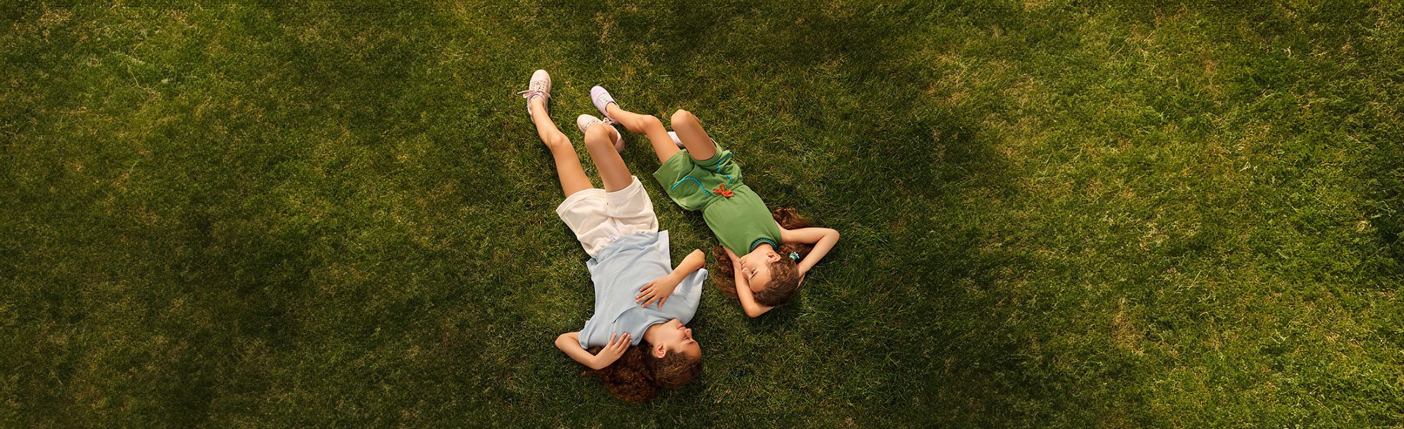 Two sisters laying in the grass talking