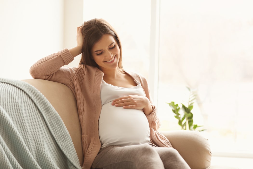 Pregnant woman smiling while sitting on the couch